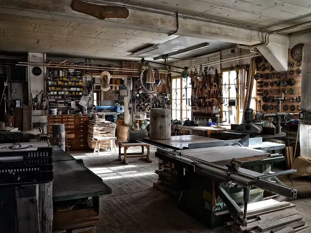 A cluttered but functional carpenters' workshop with various woodworking machinery and tools, highlighting the importance of safety in such environments.